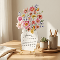 Floral-themed calendar on a wooden table with decorative items.