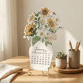 Floral-themed calendar on a wooden table with decorative items.