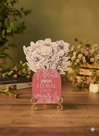 Floral-themed 2026 calendar on a stand with decorative flowers against a blurred floral background.